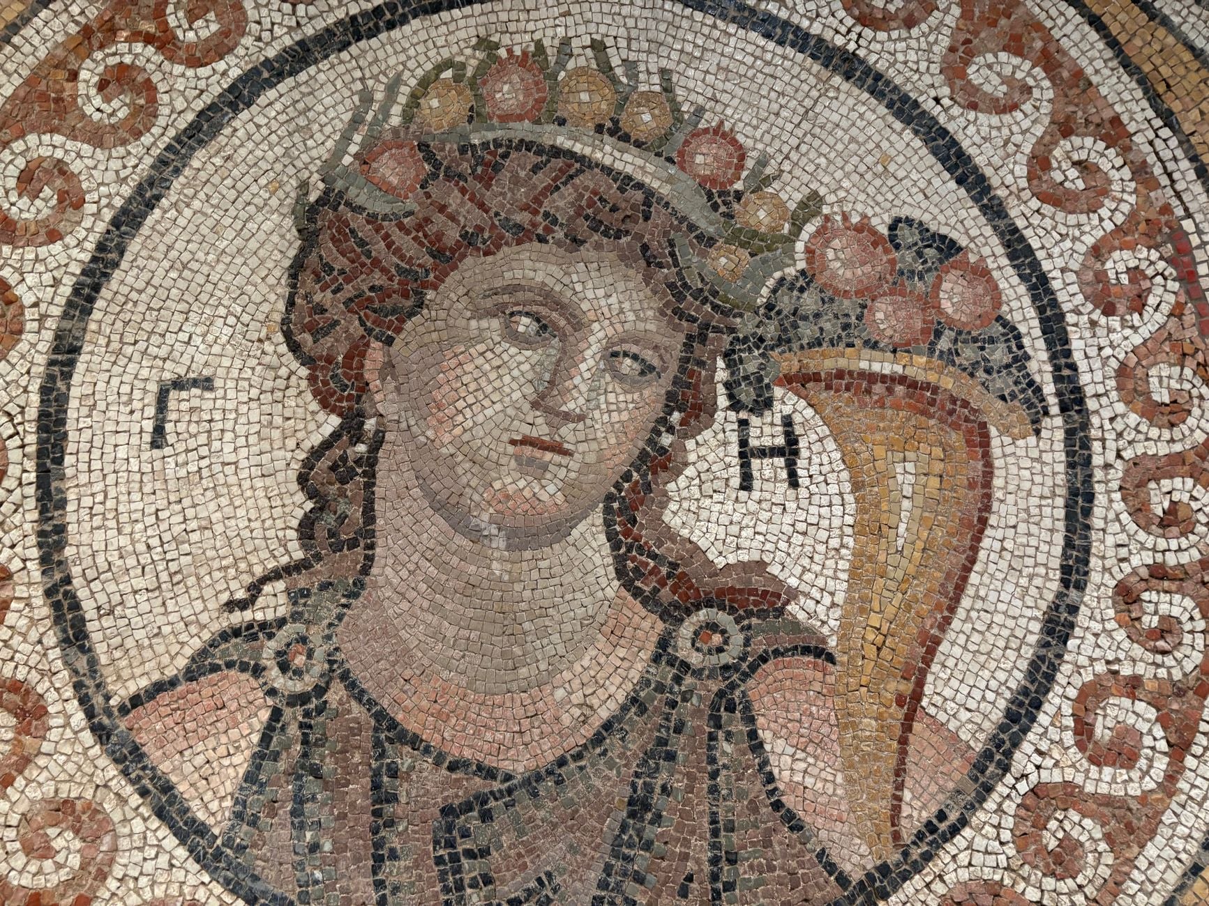 Intricate ancient mosaic depicting a mythological figure with a cornucopia, showcasing classical artistry.