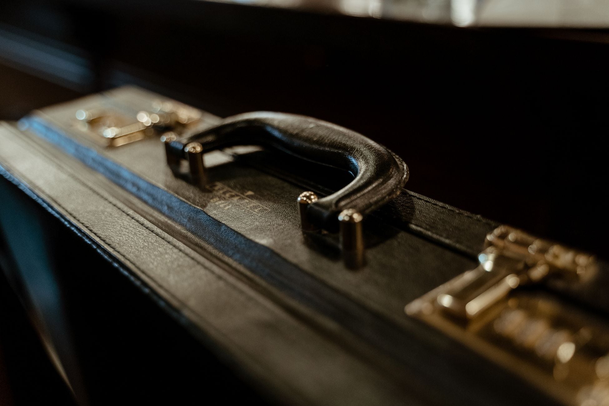 A detailed close-up of a stylish leather briefcase handle, with vintage aesthetic lighting.