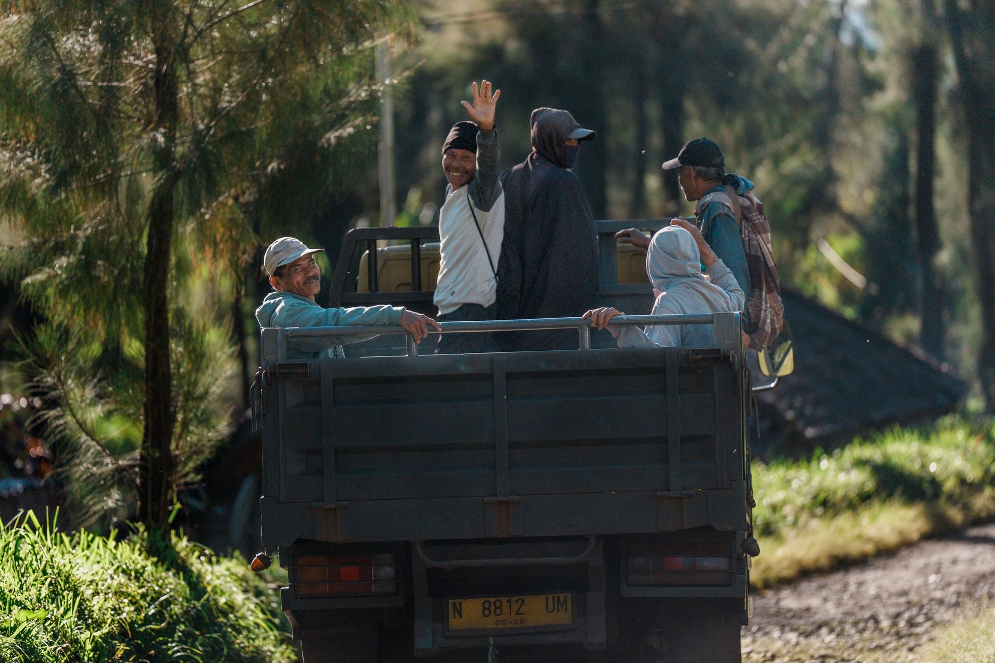 A group of people ride in a truck through lush vegetation in East Java, Indonesia.