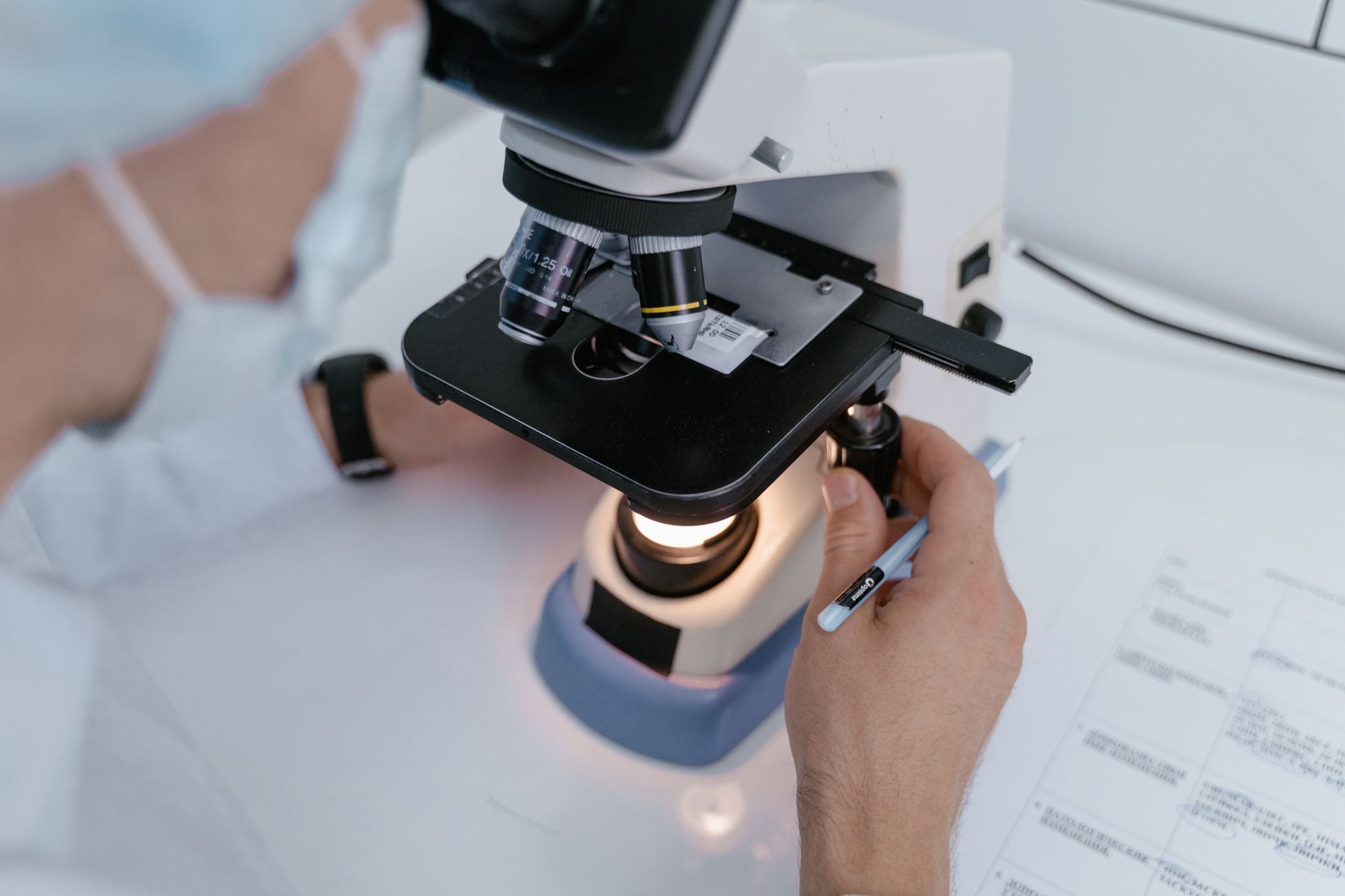 Close-up of a scientist examining samples under a microscope in a laboratory setting.
