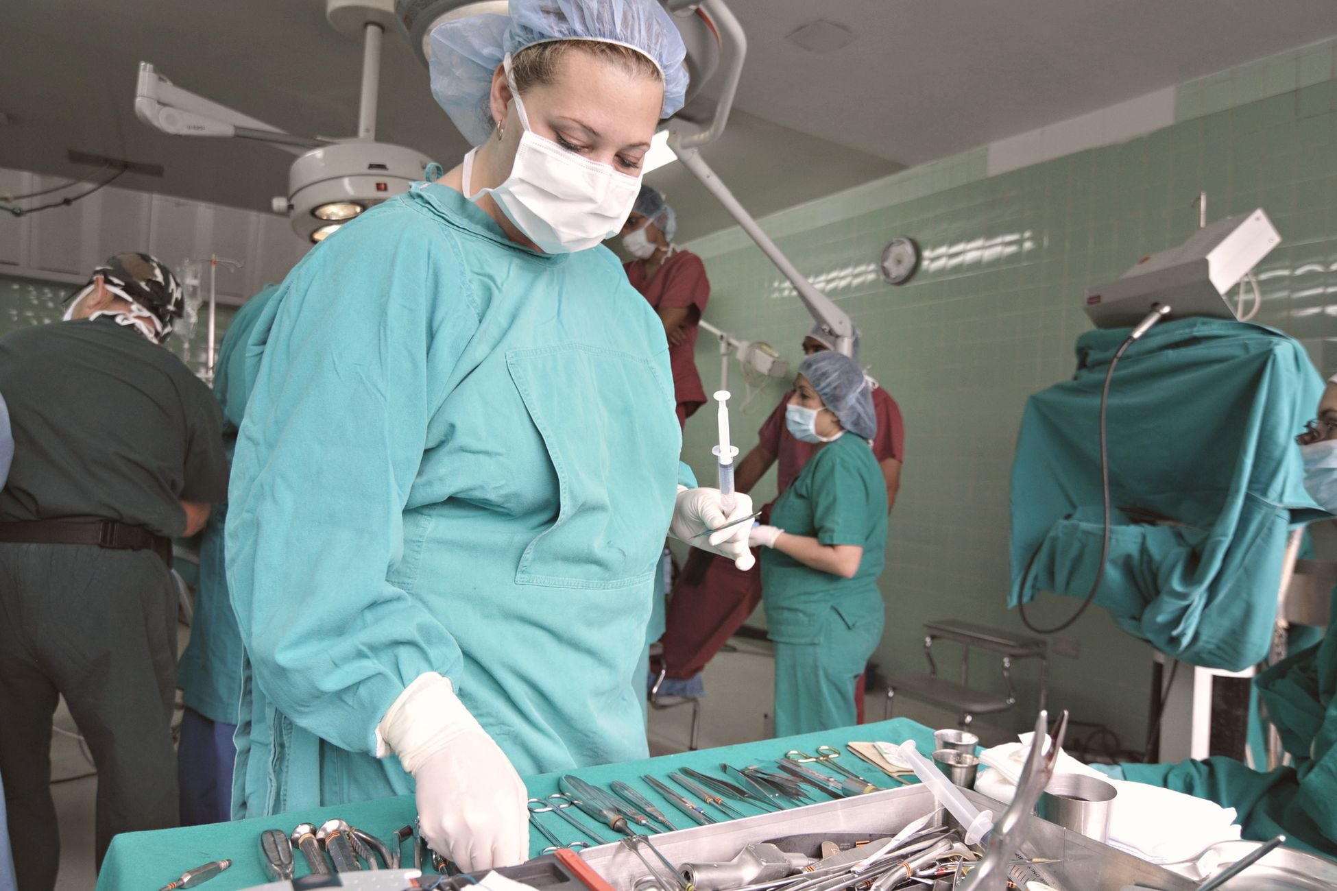 Surgeons and nurses in an operating room preparing for surgery with medical tools.
