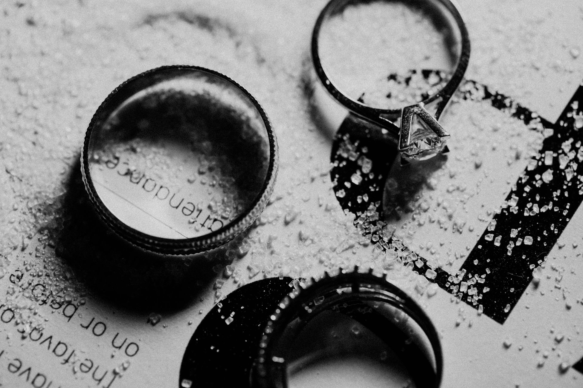 Elegant black and white image of engagement and wedding rings on textured background, symbolizing romance and commitment.
